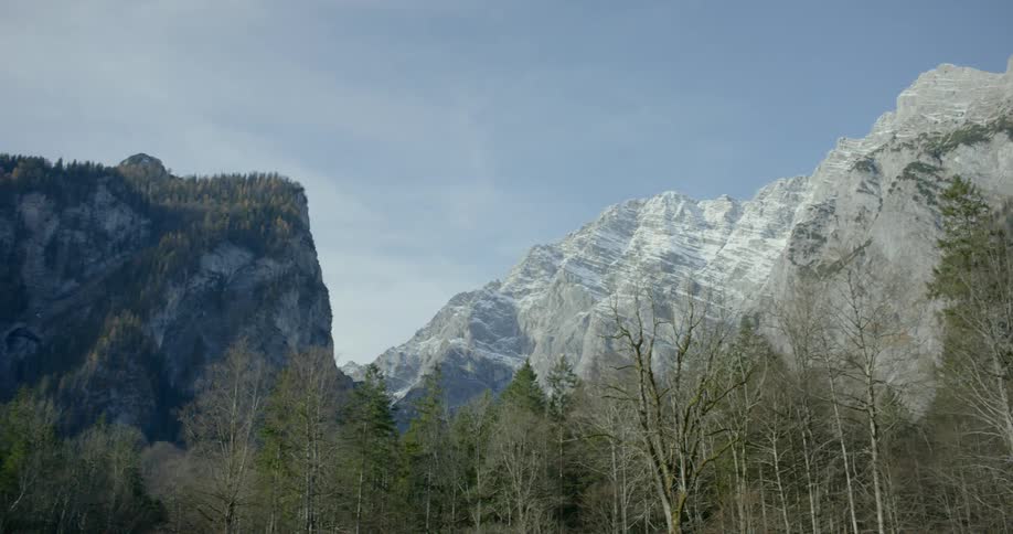 Snow covered mountains sit under the cloudy blue sky