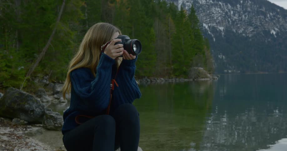 A woman sits on the shoreline and takes pictures