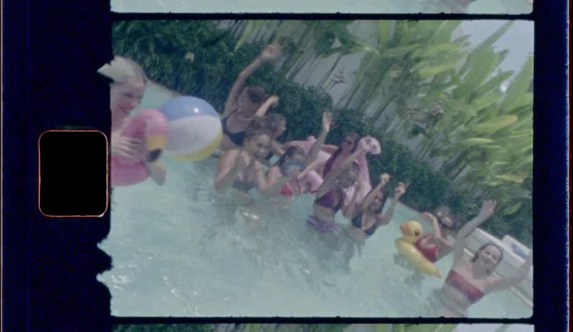 A group of women play in a pool while staring at the camera