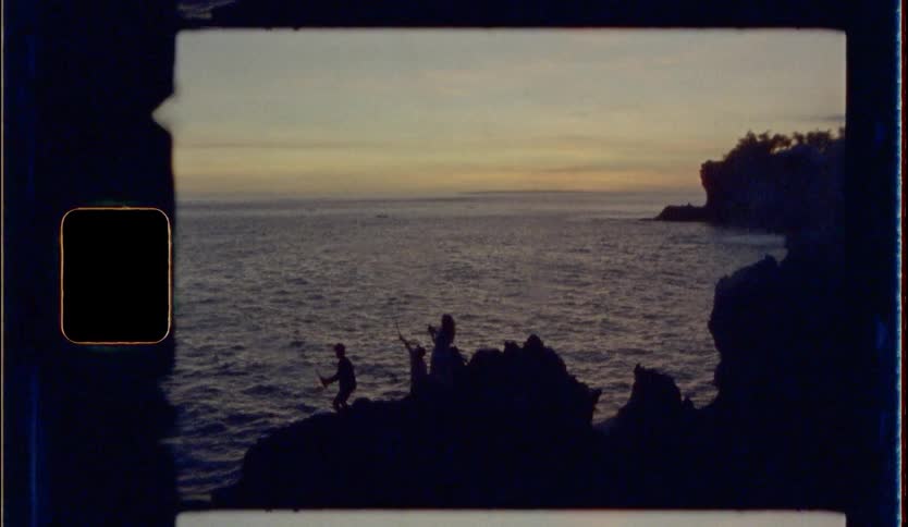 Silhouette of people shooting fireworks on a cliff at the beach