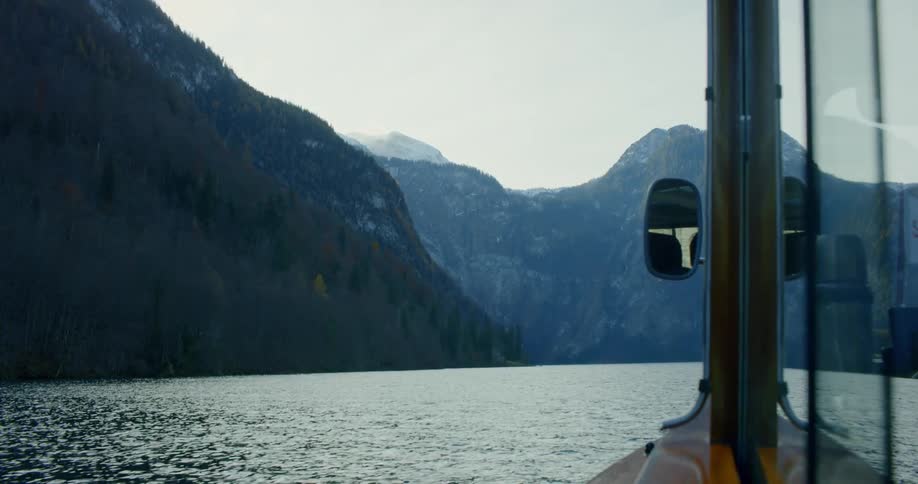 A boat sails through the water below a mountain range