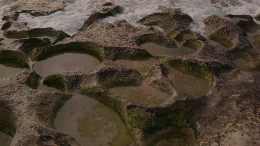 Waves crash onto rocks at the bottom of a cliff
