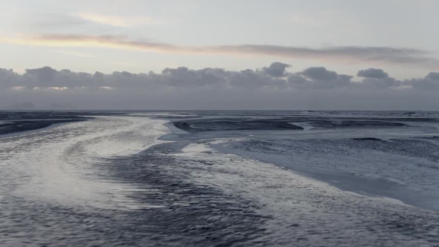 A layer of ice and snow sits on top of a vast body of water