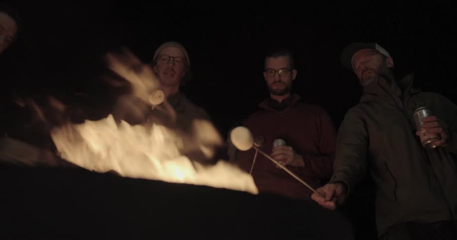 A group of people roast marshmallows over a fire