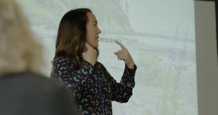 A teacher teaching in class with slideshow behind