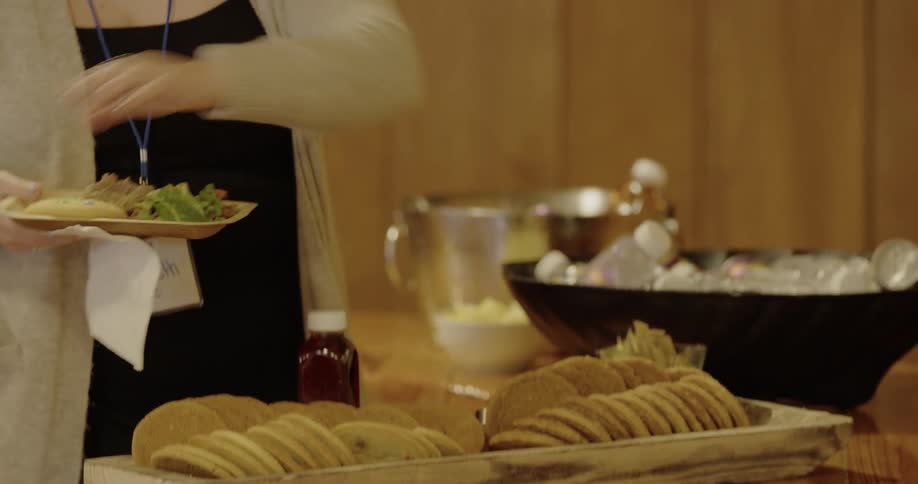 A woman picks up a cookie and places it on a food plate