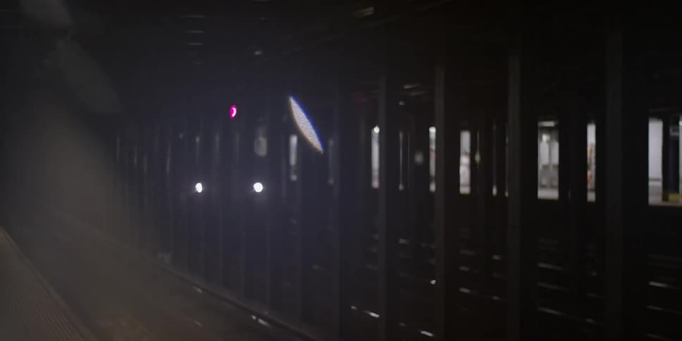 A train is entering a dark train platform