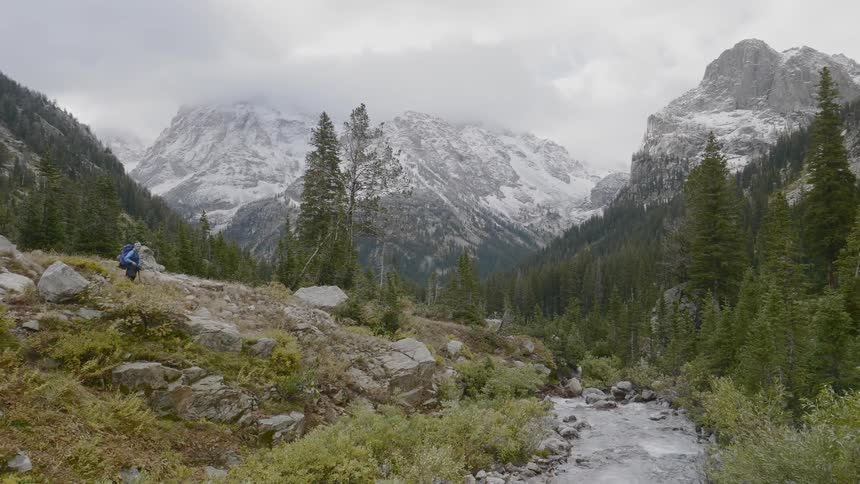 A person hikes towards a stream