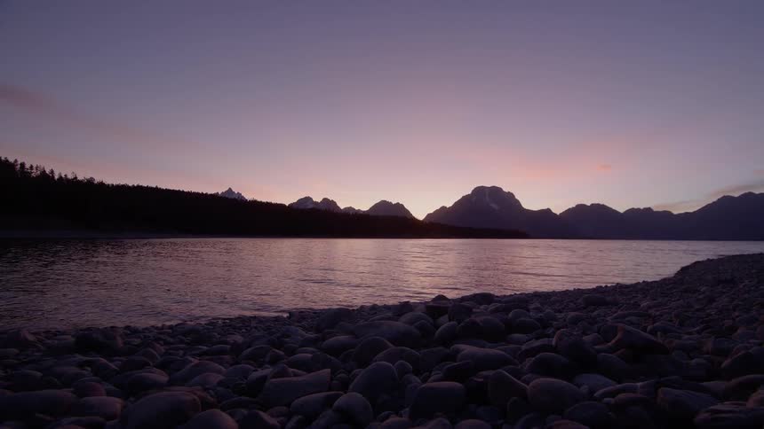 Landscape view of a lake in front of the mountains as the sun sets