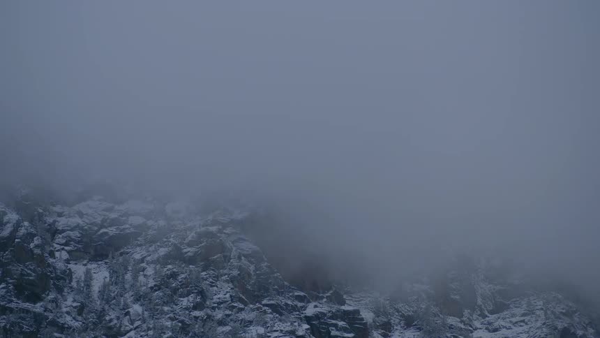 Mist flows over a rocky mountain face