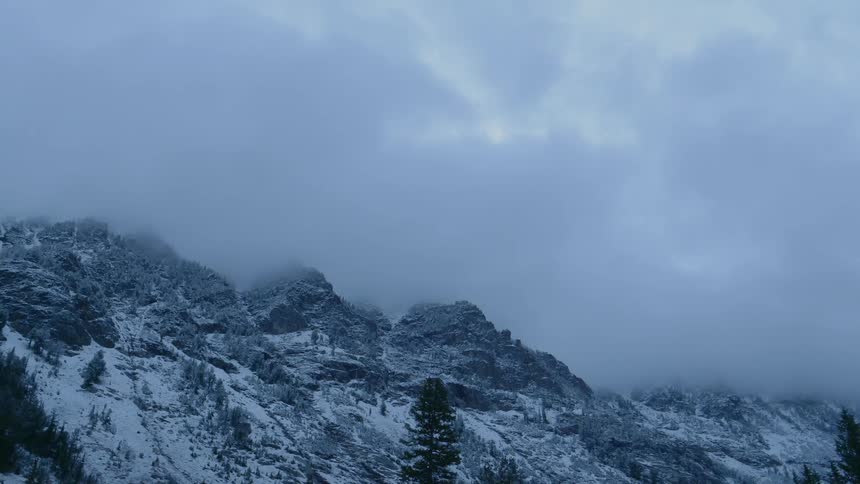 Clouds move over snowy mountains