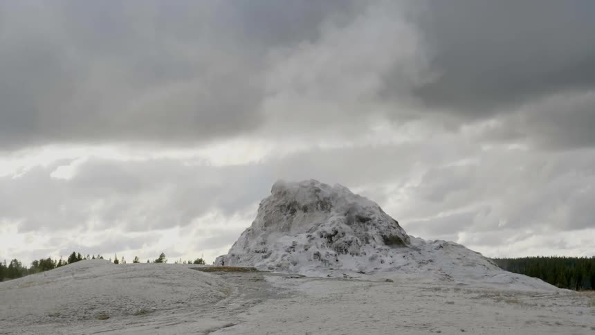 Steam rises from a hill under a cloudy sky