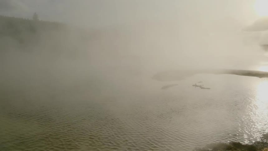 A hot spring with steam and water shimmering in the sunlight