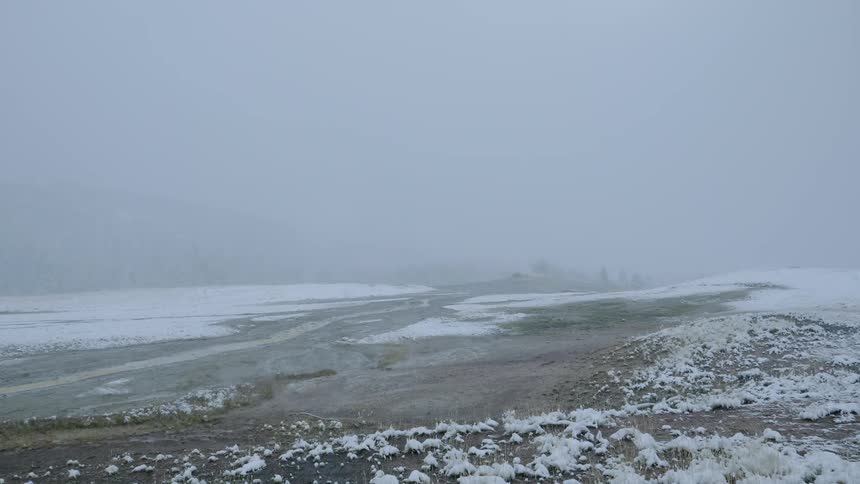 Snow falling over flat land