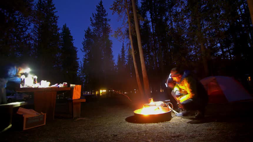 People at a campsite cooking on a grill