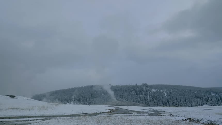 Steam rises from geothermal features in a winter landscape