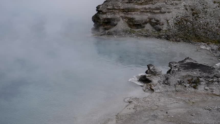A natural hot spring surrounded by black rock