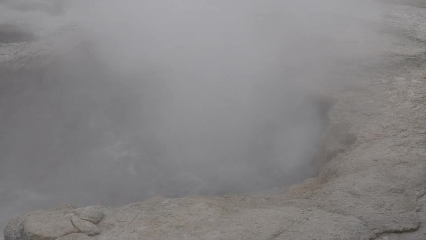Water in a natural spring in the ground is boiling away quite vigorously while producing a constant plume of steam
