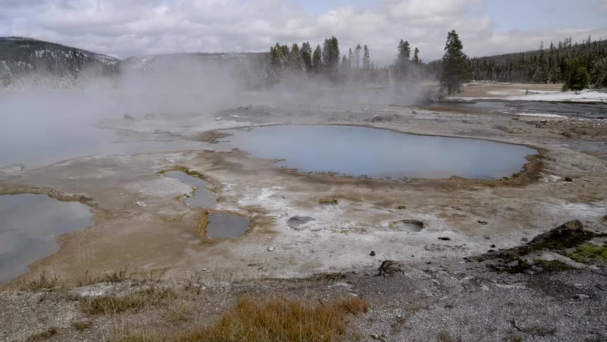 Steam billows over hot springs set in the landscape