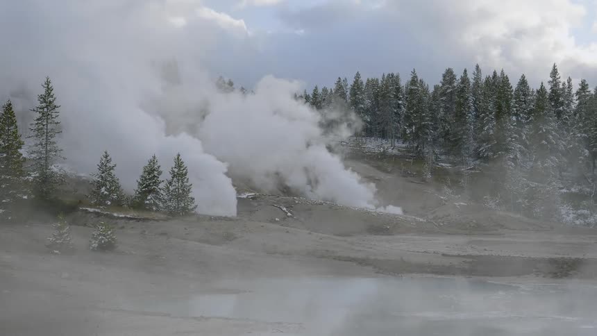 Huge plumes of steam billow up from the ground at a natural hot spring that is located in the middle of a clearing in the snow covered forest