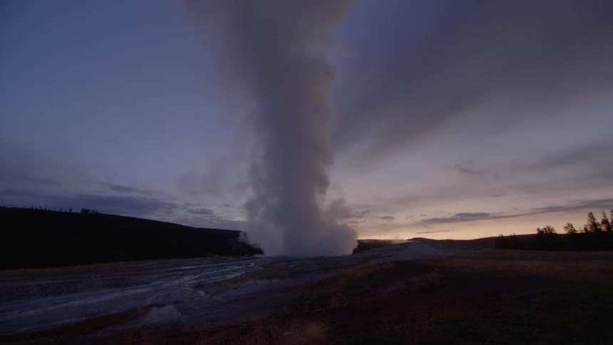 Steam flows rapidly up into the sky at sunset from a geyser