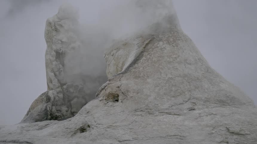 Steam rises from a rocky formation