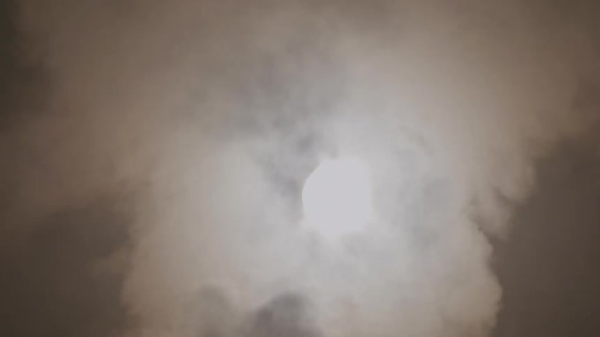 Fog rises up in front of a full moon