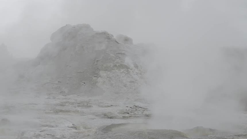 Steam billowing from holes in the ground of a rocky terrain