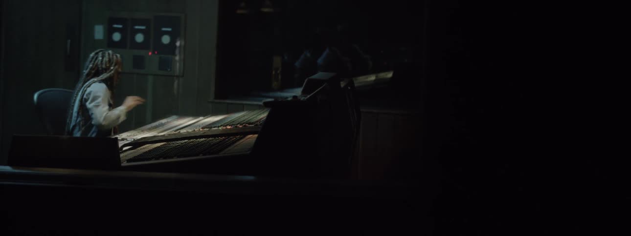 A young woman works on a sound board in a recording studio
