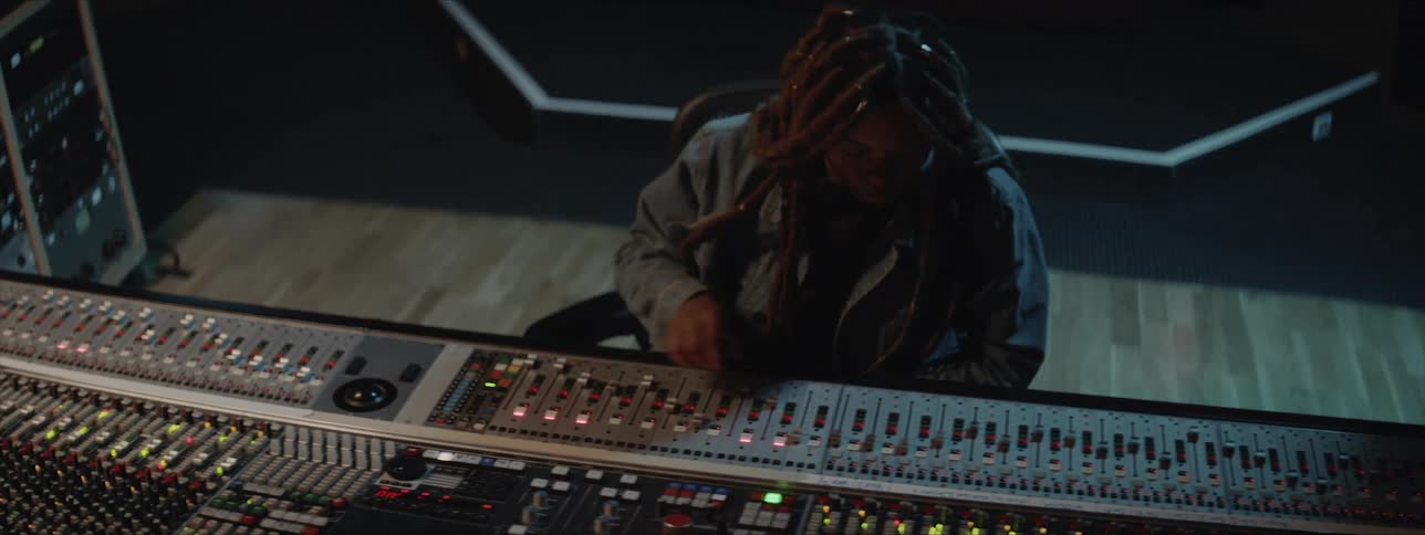 A woman sits and controls a sound board
