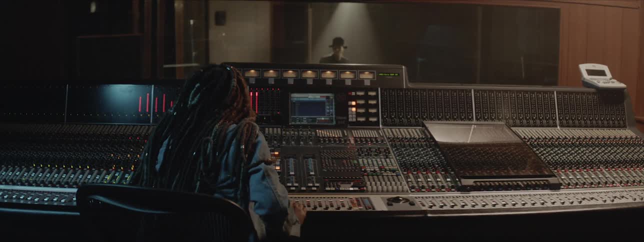 A person is working the sound board in a studio as a person performs