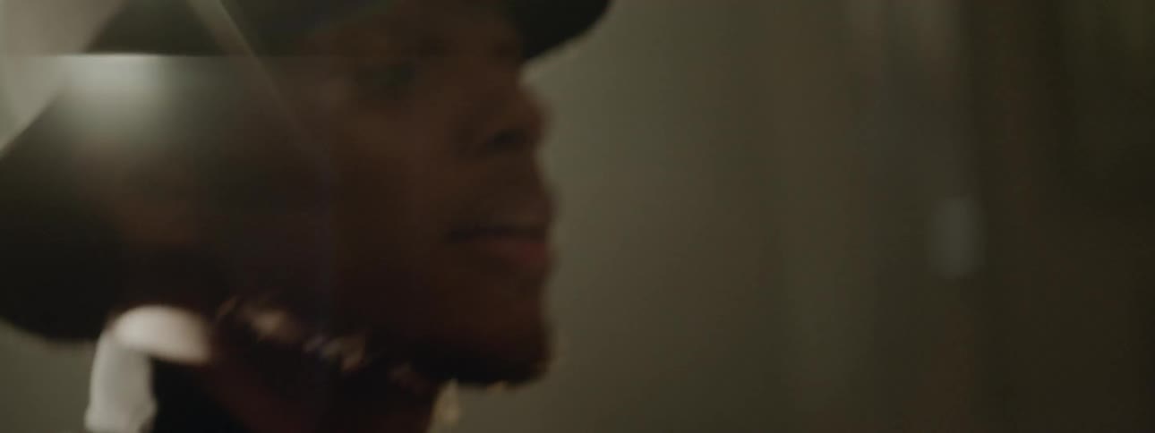 Black drummer wearing black hat plays drums at the stage