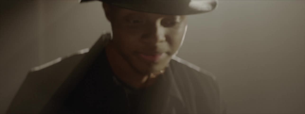 A man with a black hat and shirt playing drums