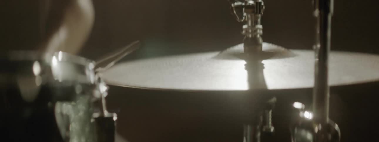 A drummer plays as the hi hat reflects light