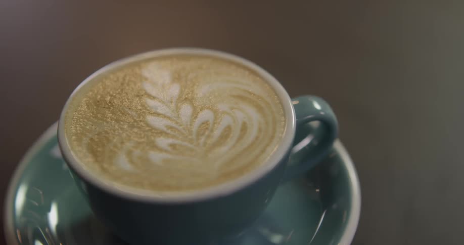 Latte leaf design in blue cup on the brown table
