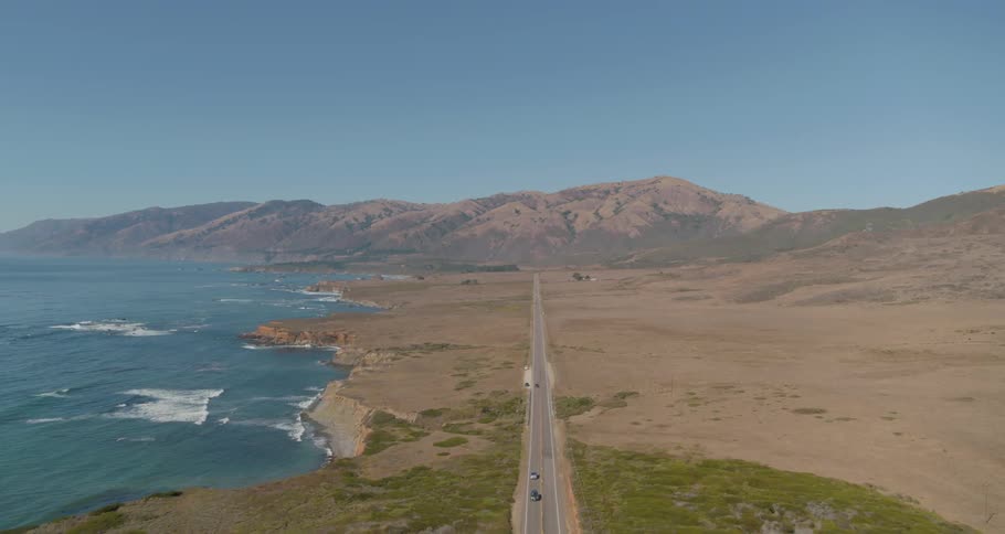 Vehicles travel a long highway beside the ocean coast