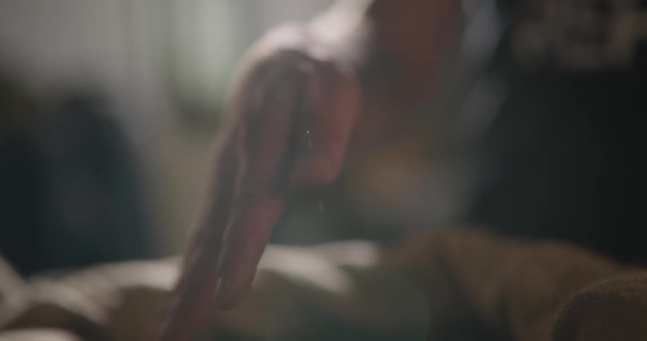 A man picks up a handful of coffee beans from a burlap bag and sifts them through his fingers
