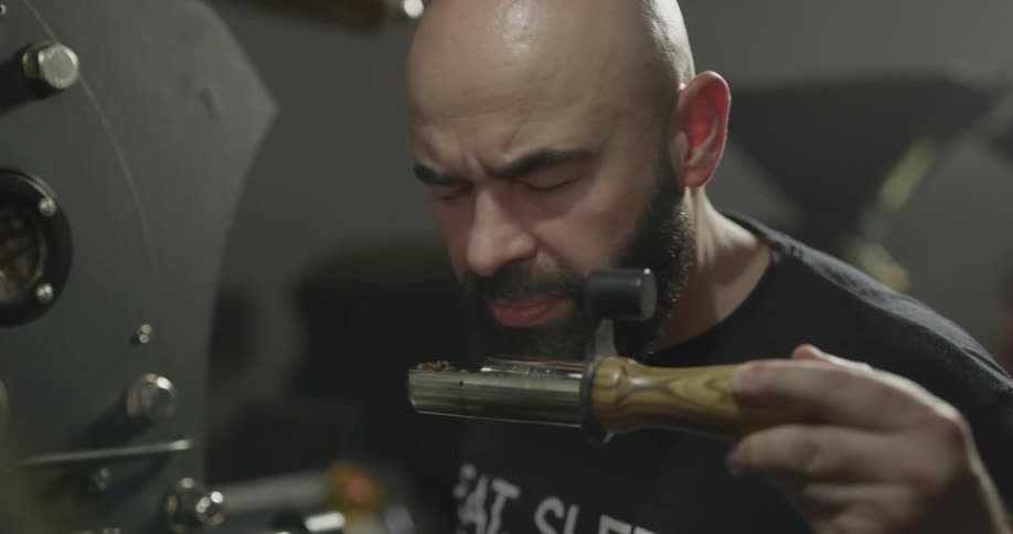 A man turns a handle and smells the inner pieces