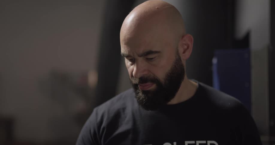 Bald bearded man uses macbook indoors