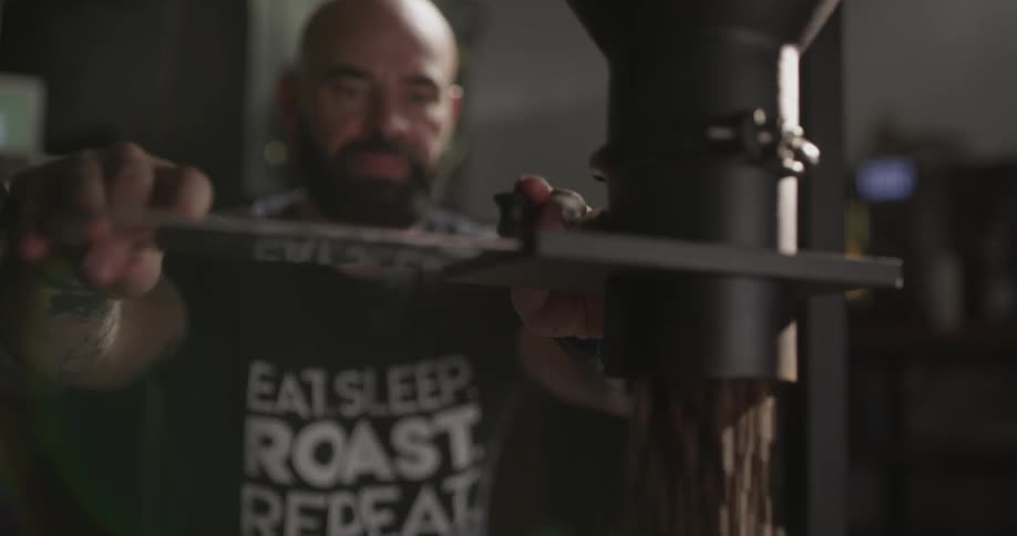A man removes a lever and coffee beans fall out of a machine