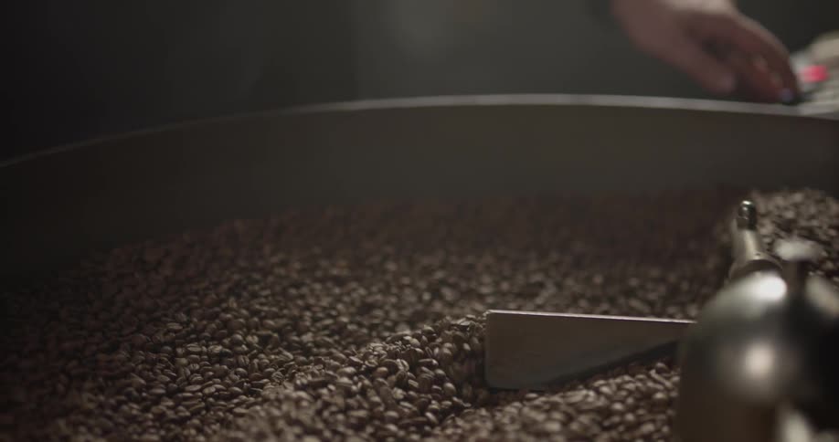A person operating a machine stirring coffee beans