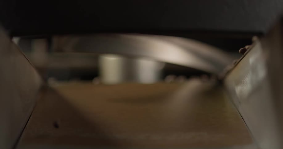 Coffee beans are pushed down a chute by a rotating arm