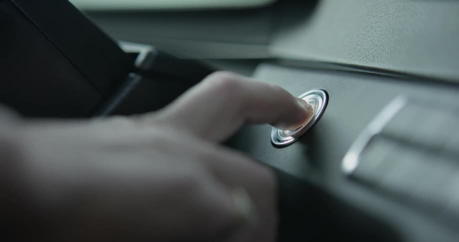 A woman pushes the button to start her car