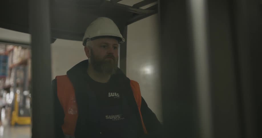 A man moves large boxes using a forklift in a warehouse