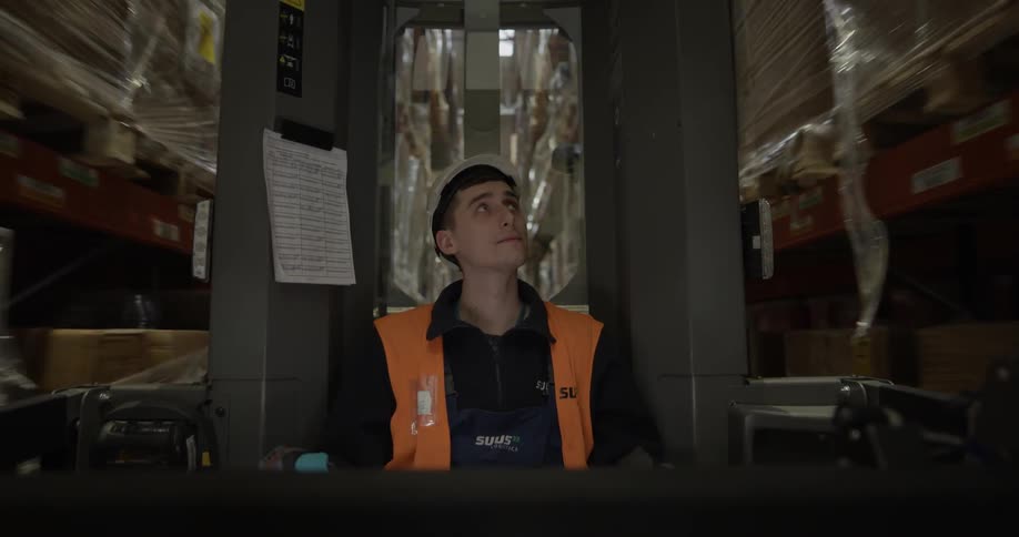 A young man backs a vehicle up in a warehouse