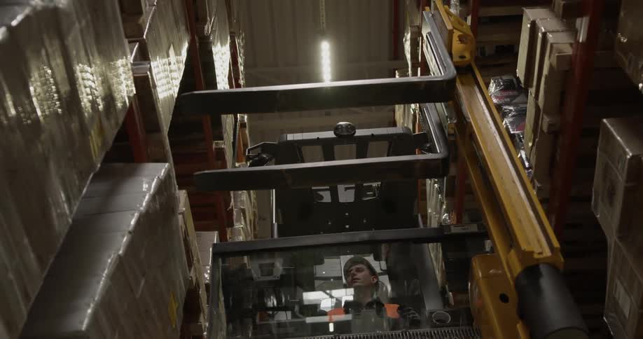 A man is loading pallets in the warehouse with a forklift