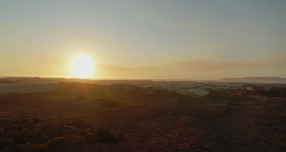Aerial view of sand dunes near the ocean at sunset