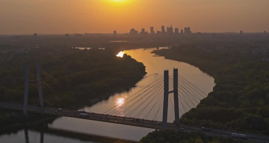 Birds eye view of a cars driving across a bridge with the city in the background