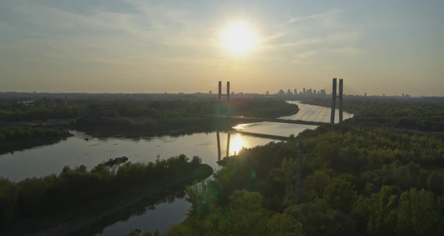 A river with a bridge with the sky and the city in the background