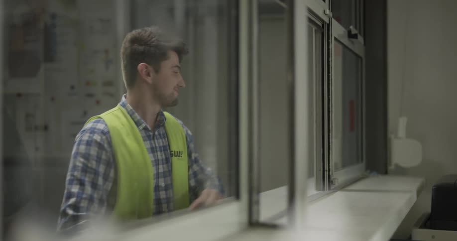 A woman walks up to a counter and shows the worker a piece of paper which he scans